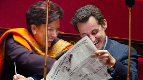 Der damalige Innenminister Nicolas Sarkozy und Umweltministerin Roselyne Bachelot lachen beim Lesen der Satirezeitschrift "Le Canard enchaîné" während einer Sitzung der Nationalversammlung in Paris am 18. Dezember 2002