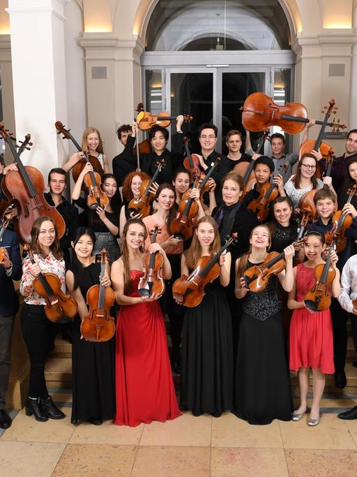 Die Preisträger des Deutschen Musikinstrumentenfonds 2018 haben sich zu einem Gruppenbild versammelt und strecken ihre Streichinstrumente in die Höhe.