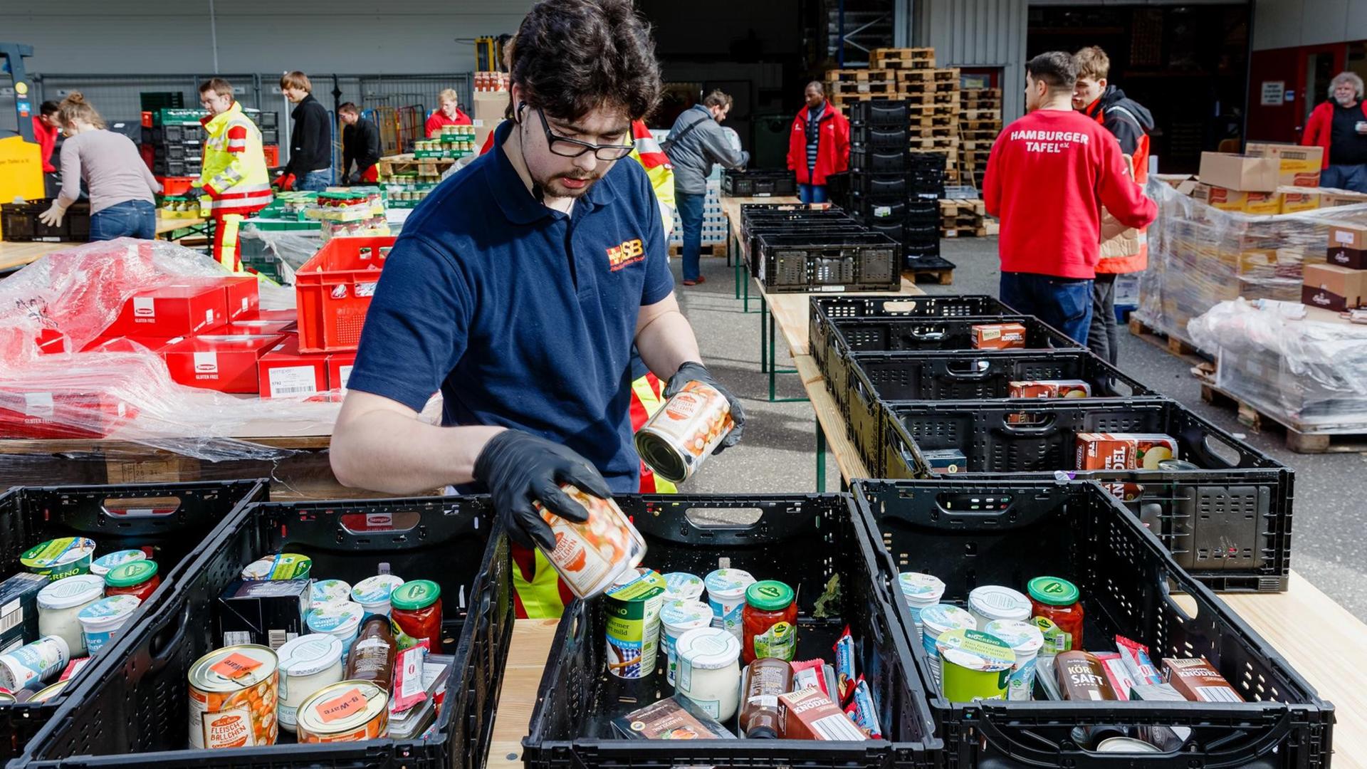 Ehrenamtliche Helfer des Hamburger Tafel und des Arbeiter-Samariter-Bunds packen im Zentraldepot Kisten mit Lebensmitteln für die Ausgabestellen der Tafeln.