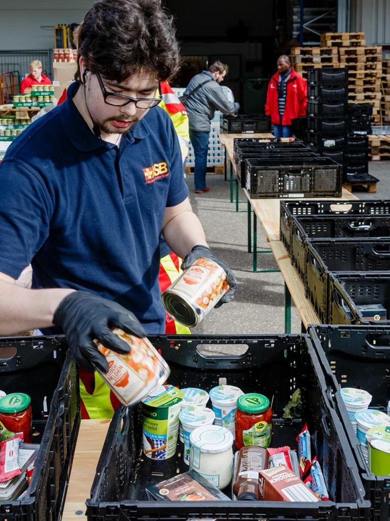 Ehrenamtliche Helfer des Hamburger Tafel und des Arbeiter-Samariter-Bunds packen im Zentraldepot Kisten mit Lebensmitteln für die Ausgabestellen der Tafeln.