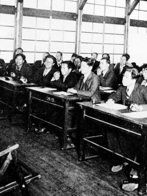 Das Bild zeigt japanische Studierende, die in einem Klassenraum eine Lehrer beobachten, der eine Vasen-Form vorführt.