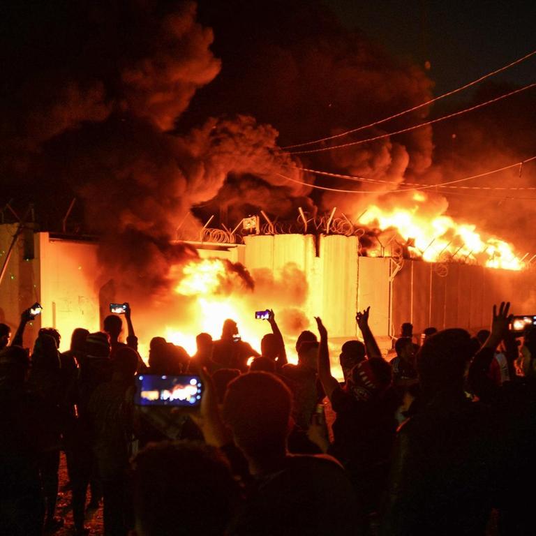 Demonstranten stehen vor dem brennenden Gebäude des iranischen Konsulat im Süden des Irak. 


