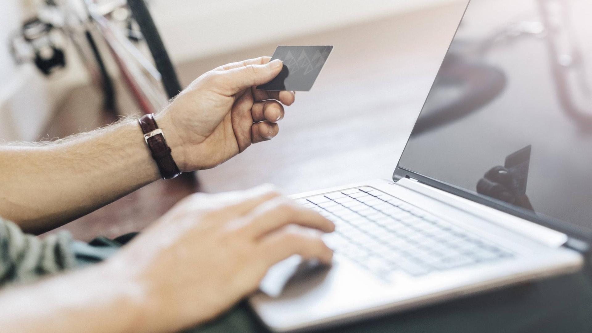 Man sitting on the floor paying online with credit card, partial view model released Symbolfoto property released PUBLICATIONxINxGERxSUIxAUTxHUNxONLY GIOF03168