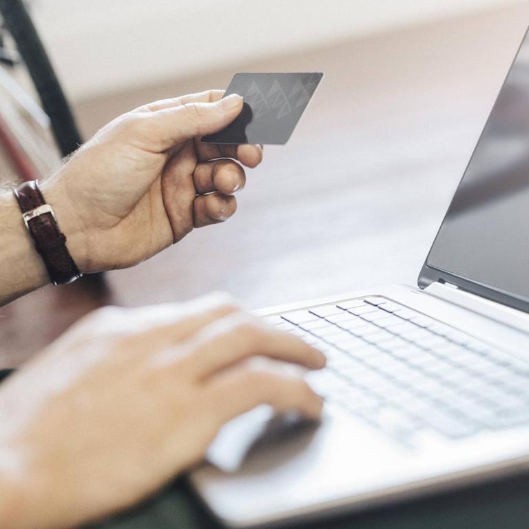 Man sitting on the floor paying online with credit card, partial view model released Symbolfoto property released PUBLICATIONxINxGERxSUIxAUTxHUNxONLY GIOF03168