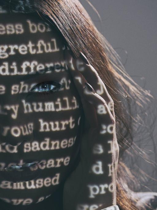 Frau mit geschriebenen Wörtern im Gesicht als Symbolbild für Depressionen und Hilflosigkeit