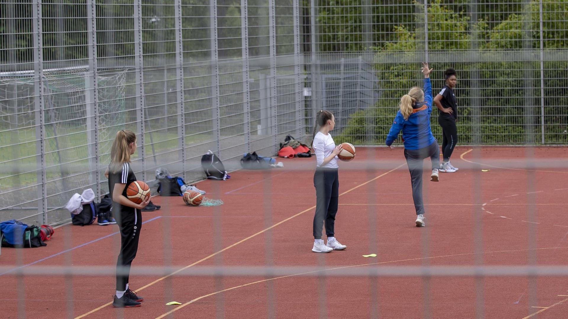 Schülerinnen in Würzburg auf einem Basketballplatz im Freien.