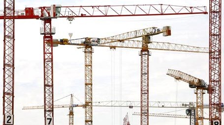 Riesige Baukräne drehen sich   auf der Baustelle des Überseequartiers in der Hafencity in Hamburg in verschiedene Richtungen.