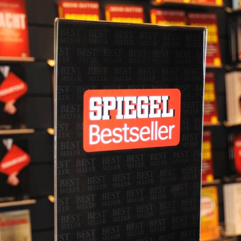 Ein Bücherregal mit Bestsellern auf der Frankfurter Buchmesse, davor ein Schild mit dem "Spiegel Bestseller" Logo. 