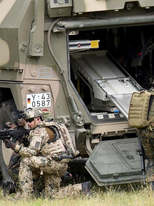 Soldaten bergen während einer Übung einen Kameraden, der einen verletzten Soldaten simuliert, und transportieren ihn in ein gepanzertes Transportfahrzeug.