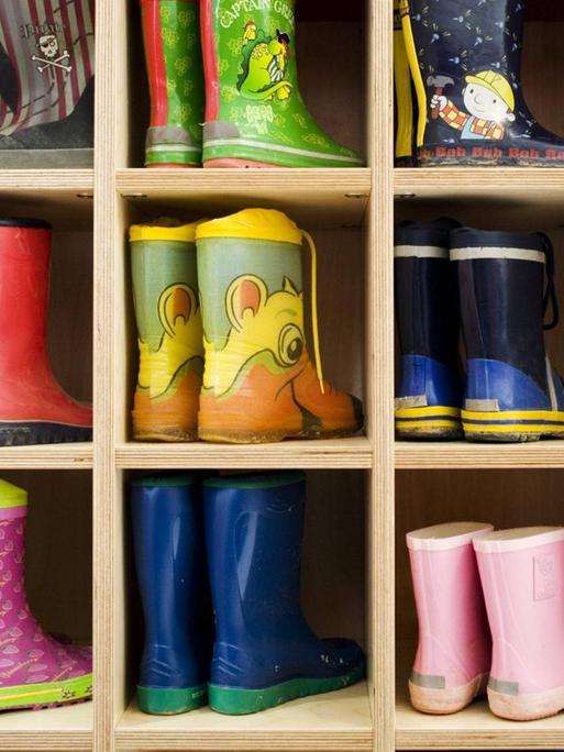 Kleine bunte Gummistiefel in der gut gefüllten Garderobe in der Kindertagesstätte