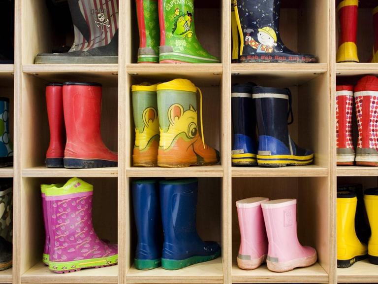 Kleine bunte Gummistiefel in der gut gefüllten Garderobe in der Kindertagesstätte