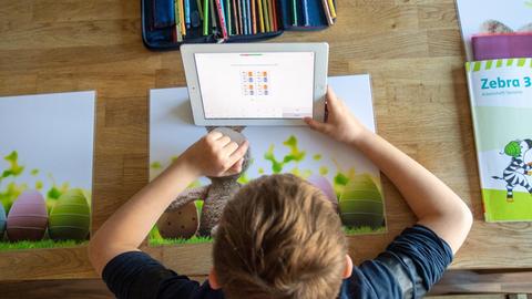 Ein Junge löst zu Hause seine Schulaufgaben am Ipad.