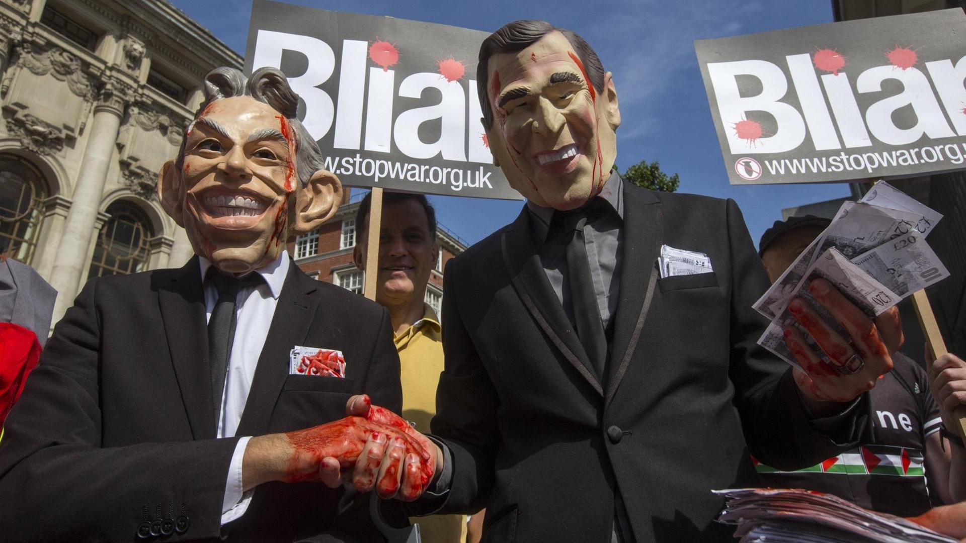 Demonstranten mit Masken von Tony Blair und George W. Bush schütteln sich rot bemalte Hände, im Hintergrund auf Plakaten das Wort "Bliar" - als Zusammenziehung von "Blair" und "Liar", also Lügner