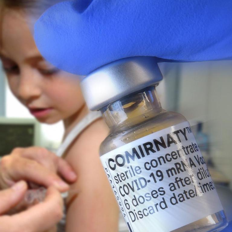 Ein Kind wird geimpft: Ein Mann drückt dazu eine Spritze in den Oberarm.
