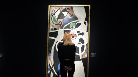 Eine Mitarbeiterin des Auktionshauses Christie's in London betrachtet am 30.1.2014 das Bild 'Femmes et oiseaux' des spanischen Malers Joan Miro, das Christie's Anfang Februar versteigern will.