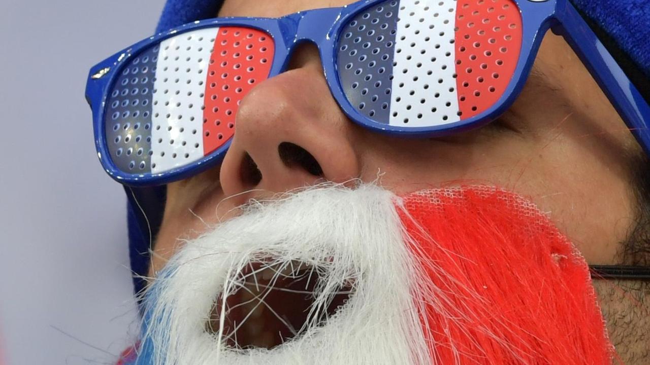 Ein französischer Fan mit Brille, Mütze und Bart in den Farben der Nationalflagge.