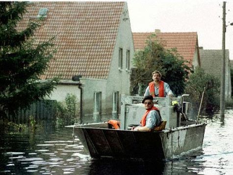 Freiwillige vom Technischen Hilfswerk (THW) fahren durch das überflutete Dorf Wiesenau an der Oder beim Hochwasser im August 1997.