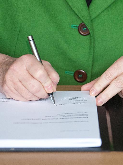 Bundeskanzlerin Angela Merkel unterschreibt den Koalitionsvertrag.