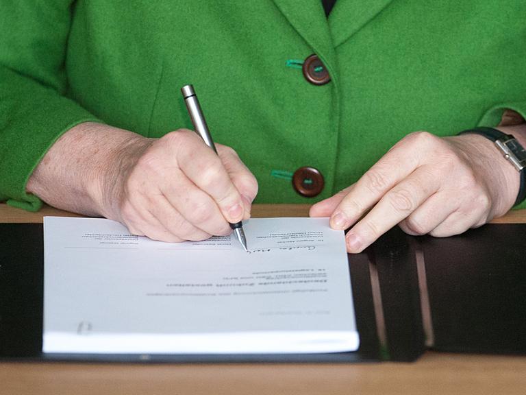 Bundeskanzlerin Angela Merkel unterschreibt den Koalitionsvertrag.
