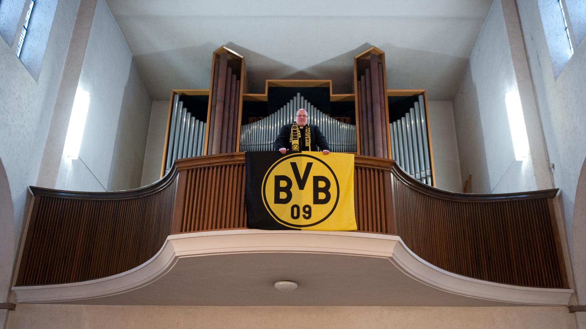 Pfarrer Ansbert Junk steht am Freitag (10.12.2010) in der Dreifaltigkeitskirche in Dortmund auf der Orgelempore, an der eine BVB-Fahne hängt. Dortmund ist ganz oben. Der Siegeskurs der Fußballer von Borussia verleiht der Ruhrgebietsstadt ein völlig neues Selbstvertrauen