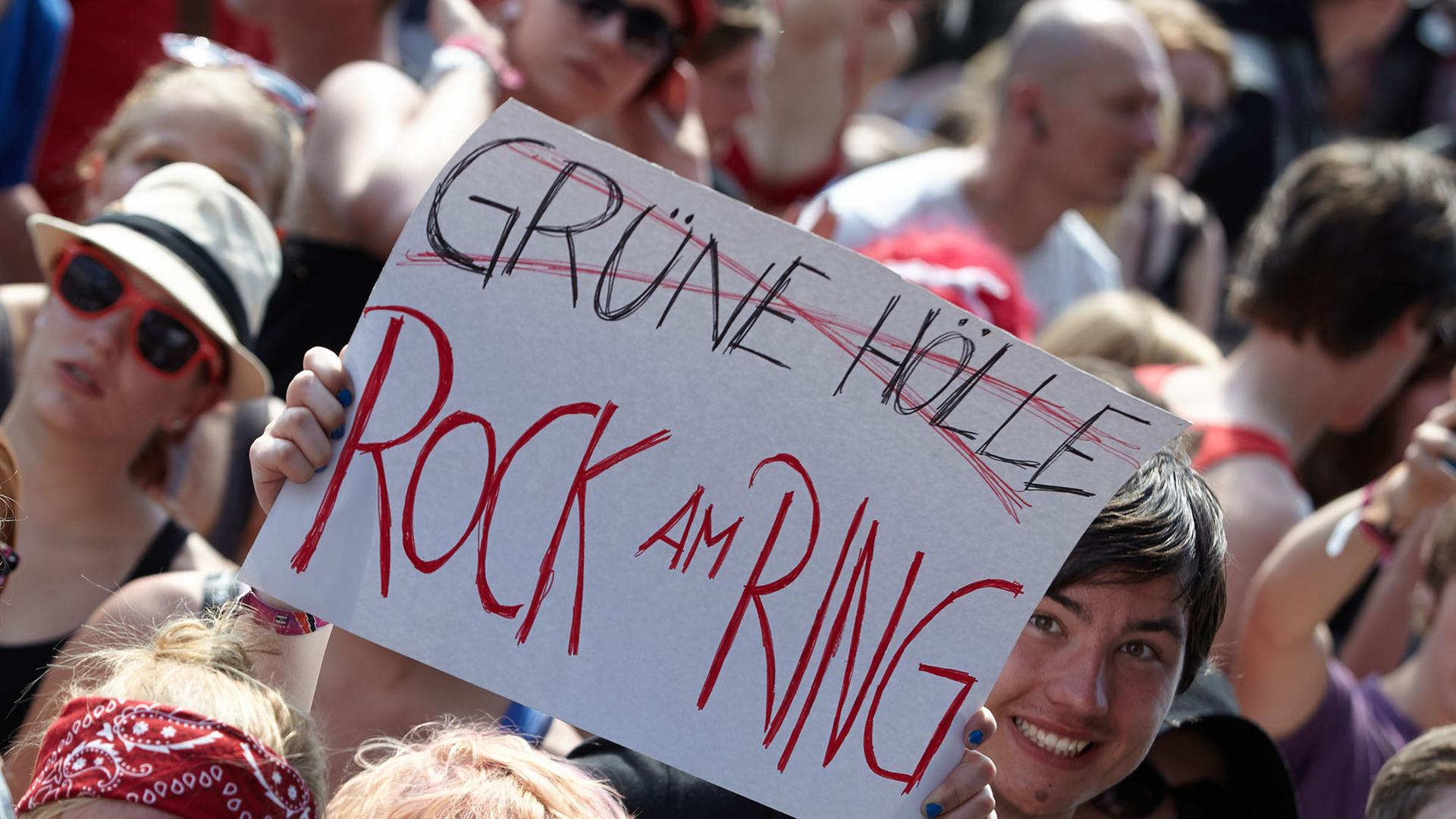 Zuschauer zeigen am 06.06.2014 beim Rockfestival "Rock am Ring" auf dem Nürburgring eine Tafel, mit der sie gegen die Nachfolgeveranstaltung "Grüne Hölle-Rockfestival" protestieren.
