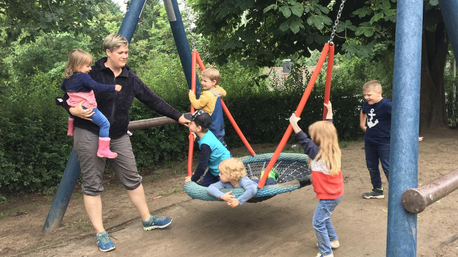Die Erzieherin Andrea Guth mit an einem Schaukelgerüst spielenden Kindern in ihrer Kita in Marnheim. Die Erzieherin Andrea Guth mit an einem Schaukelgerüst spielenden Kindern in ihrer Kita in Marnheim.