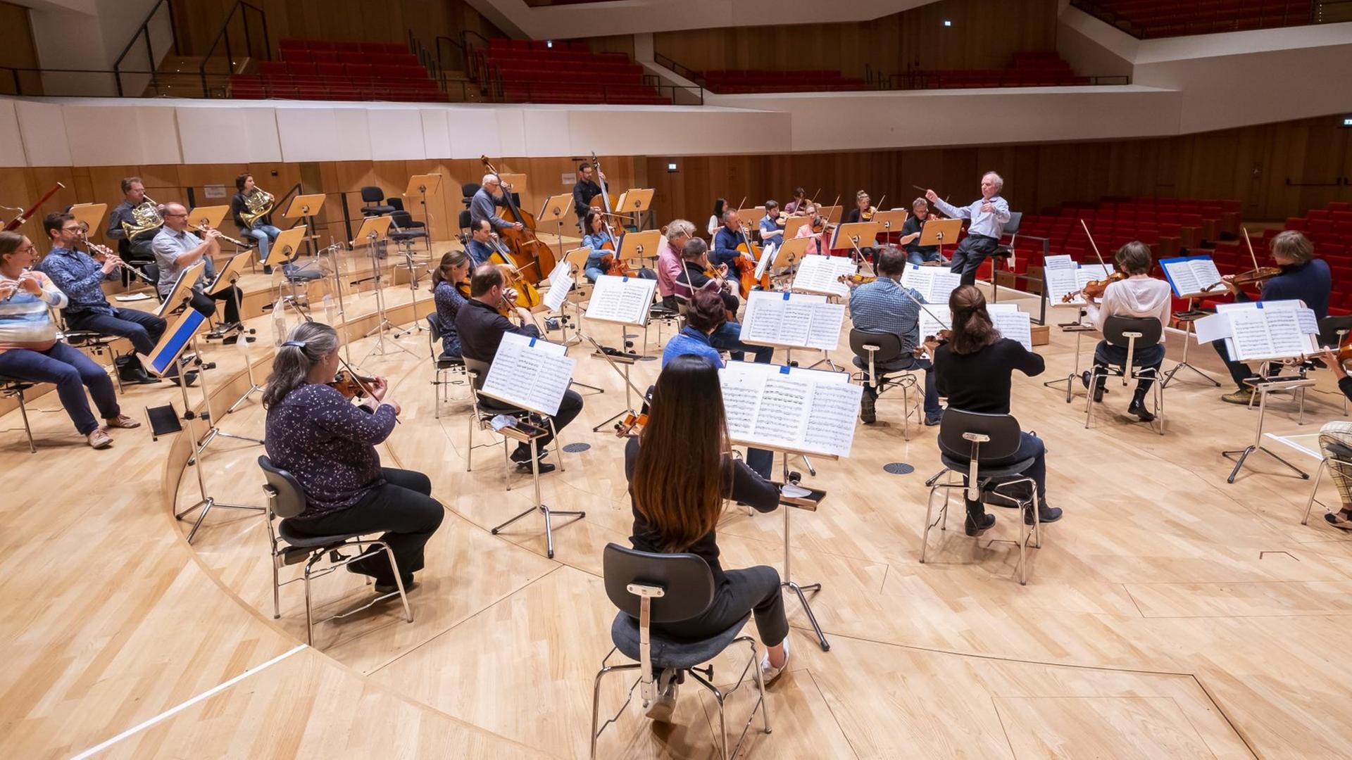 Musiker der Dresdner Philharmonie sitzen auf dem Podium im Konzertsaal des Dresdner Kulturpalastes.