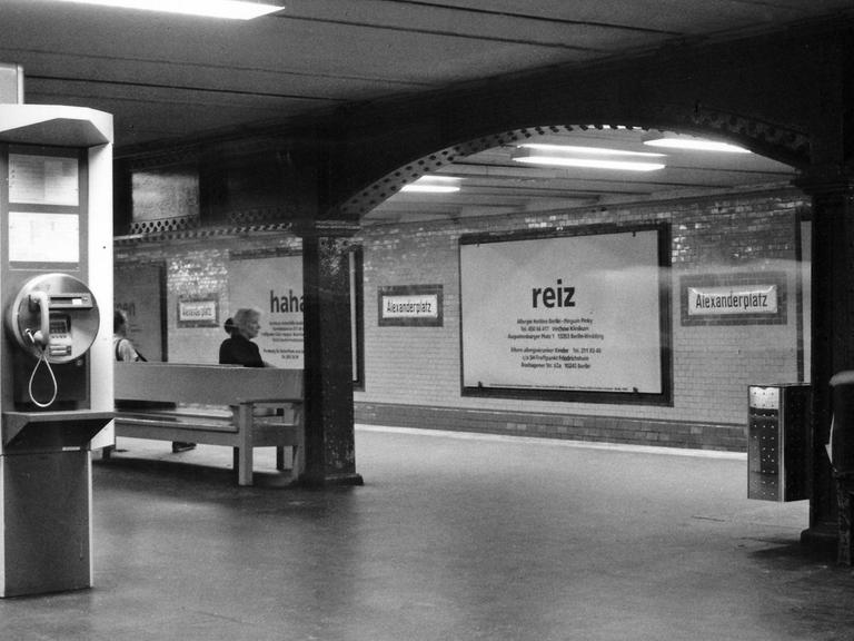 Bahnhof der Linie U2 am Berliner Alexanderplatz. Wartende Menschen, die 1998 einem großen Plakat mit dem Aufdruck "Reiz" am u-Bahn-Gleis gegenübersitzen.