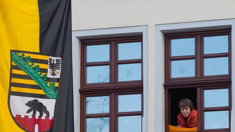 Eine Schaulustige verfolgt am Freitag (24.06.2011) das Geschehen des 15. Sachsen-Anhalt-Tages in Gardelegen (Altmarkkreis Salzwedel) neben einer Sachsen-Anhalt-Fahne.