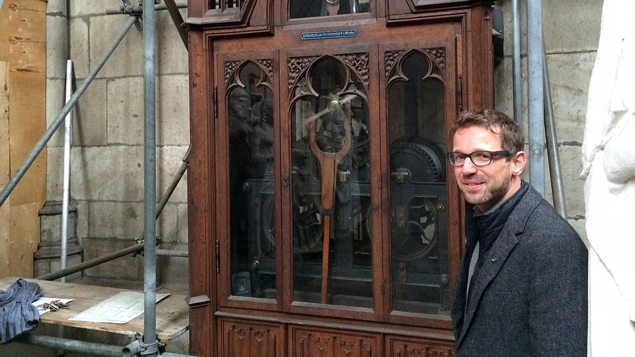 Der Kölner Dombaumeister Peter Füssenich neben dem mechanischen Uhrwerk.