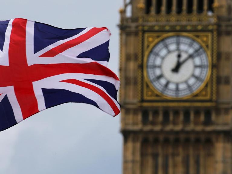 Eine Britische Fahne weht vor dem Uhrenturm Big Ben.