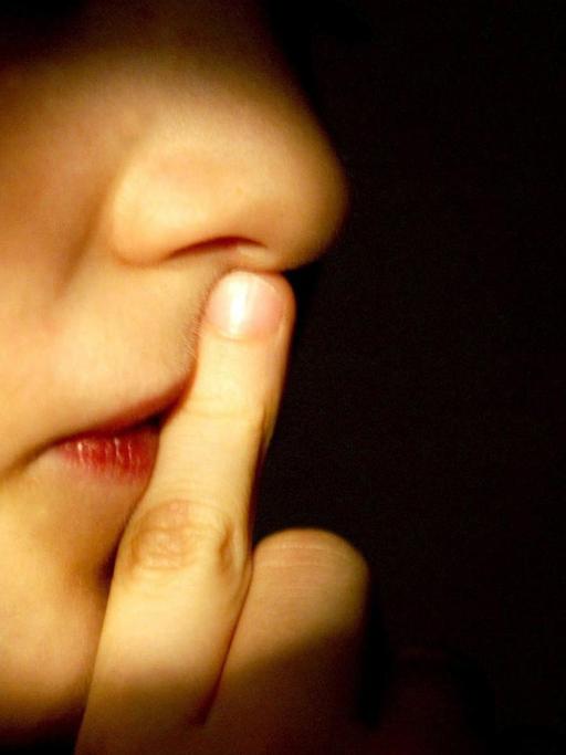 Ein Junge hält den Finger vor den Mund.