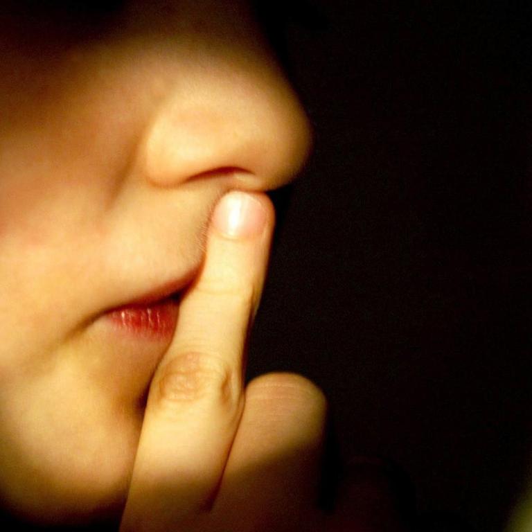 Ein Junge hält den Finger vor den Mund.