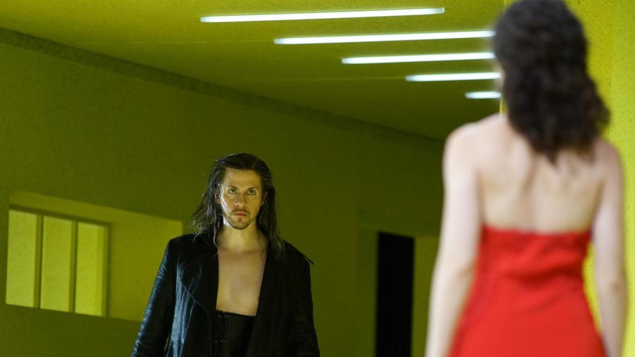 Bariton Christoph Bolduc in der Rolle des Don Giovanni fokussiert eine Frau in einem roten Kleid.
