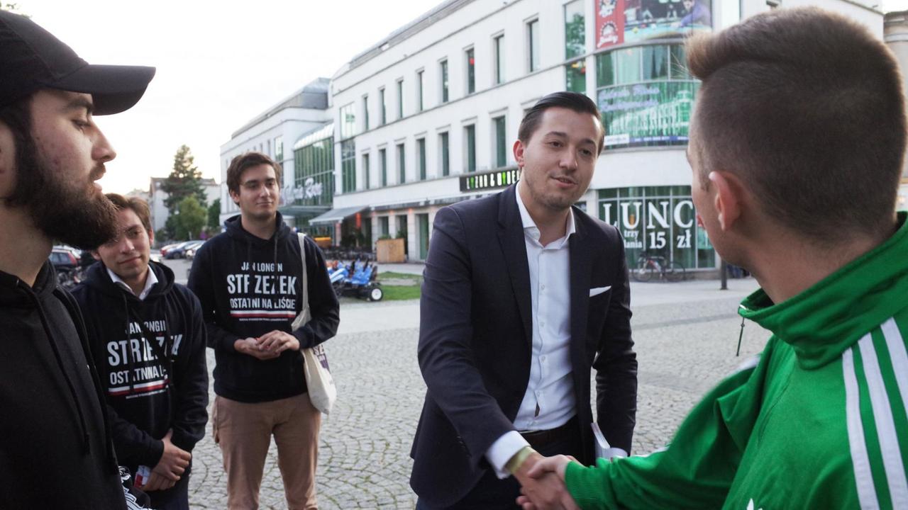 Jan Strzezek, PiS-Politiker, verteilt in der Fußgängerzone seine Flyer und Flaschenöffner