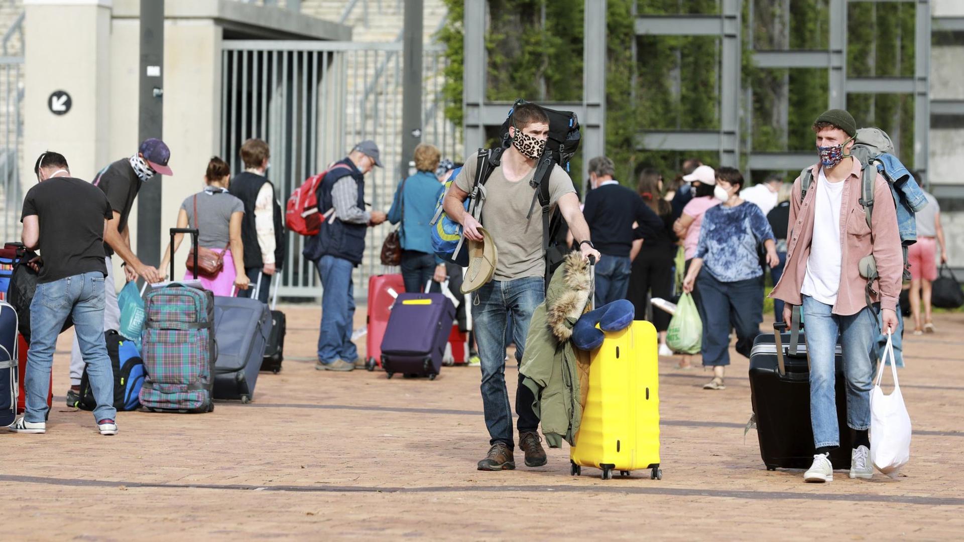 Deutsche Touristen stehen mit Gepäck im Kapstadt-Stadion, bevor sie mit einem Charterflug von Südafrika nach Deutschland reisen.