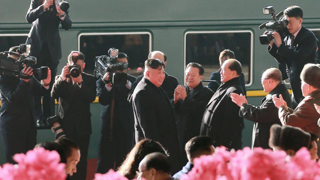 Der nordkoreanische Staatschef Kim Jong Un traf mit dem Zug in Hanoi ein. Hier steht er vor dem Zug, umringt von Fotografen und Menschen, die Beifall klatschen.
