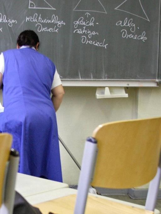 Eine Putzfrau reinigt ein Klassenzimmer in einer Grundschule in Berlin-Tempelhof.