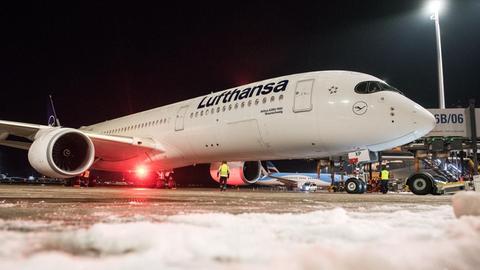 Ein weißer Airbus steht am Abend auf einem Flughafengelände. Es ist dunkel.