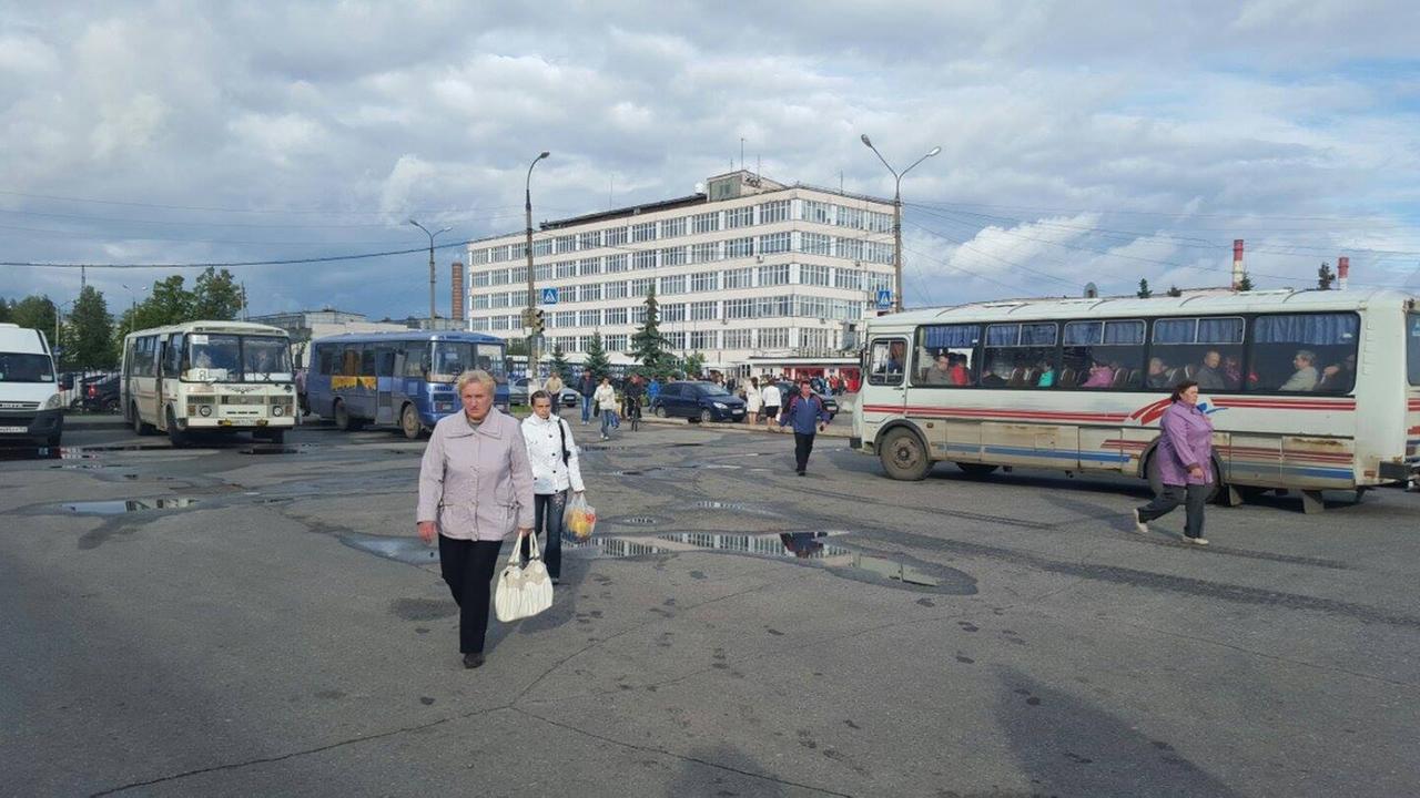 Menschen kommen aus dem Motorenwerk in Sawolschje. Vor dem baufälligen Gebäude stehen alte Busse.