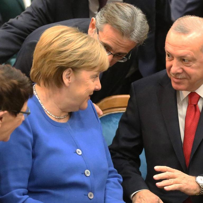 Bundeskanzlerin Angela Merkel sitzt bei ihrem Besuch in Istanbul neben dem türkischen Präsidenten Recep Tayyip Erdogan. Beide schauen sich an.