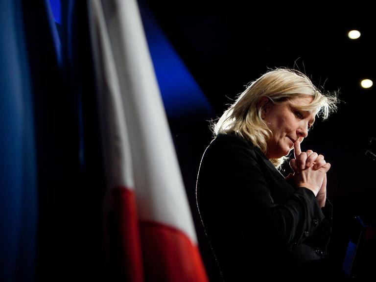 Marine Le Pen vom rechtsextremen Front National in nachdenklicher Pose, im Hintergrund die französische Flagge
