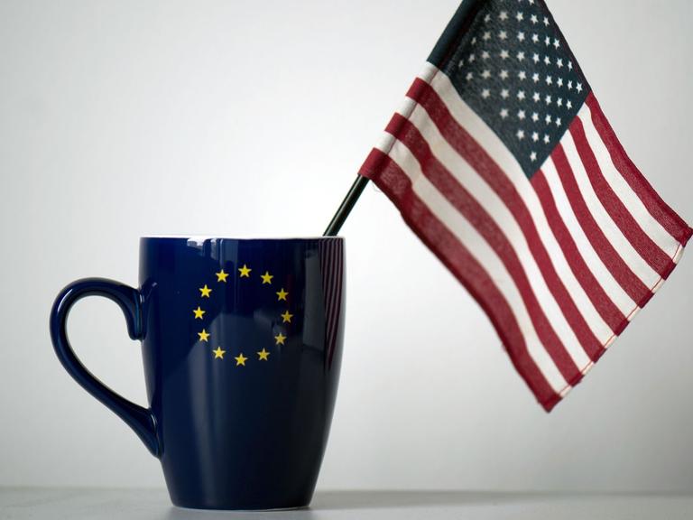 In einer Tasse mit einem EU-Symbol steckt eine US-Fahne, aufgenommen in einem Büro in Dresden.
