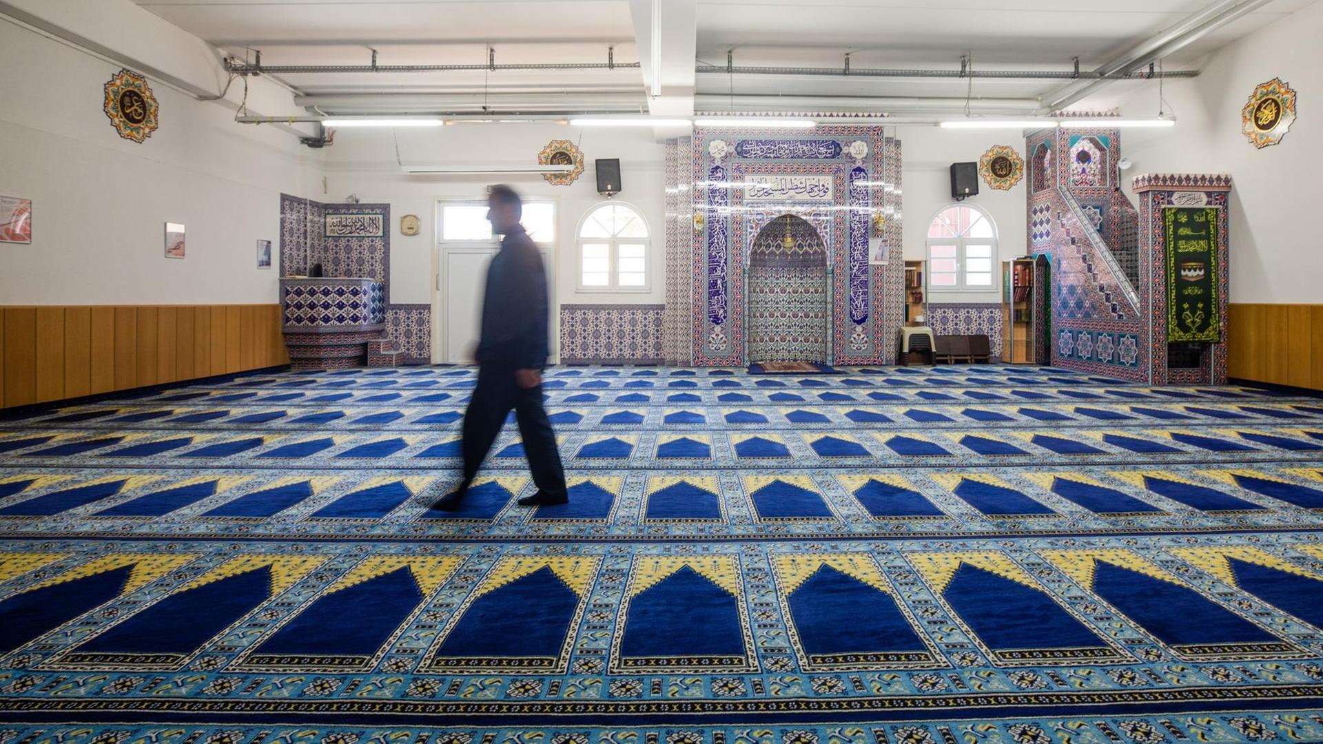 Ein Mann läuft durch einen leeren Gebetsraum einer Moschee.