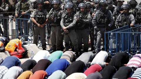 Palästinenser beim Gebet außerhalb der Altstadt von Jerusalem, beobachtet von israelischen Sicherheitskräften.