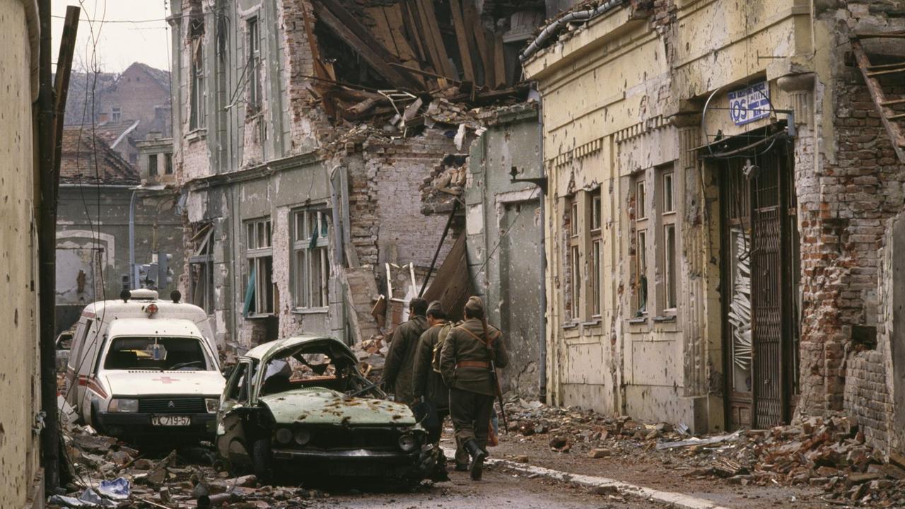 Jugoslawische Soldaten und serbische Paramilitärs, darunter Zeljko "Arkan" Raznatovic, ziehen nach einem dreimonatigen Kampf zwischen den kroatischen Streitkräften und der jugoslawischen Bundesarmee durch Vukovar an bombardierten, von Einschusslöchern durchlöcherten Gebäuden und mit Trümmern gefüllten Straßen vorbei. Die jugoslawische Bundesarmee zerstörte die kroatische Stadt vollständig und tötete Tausende von Zivilisten.