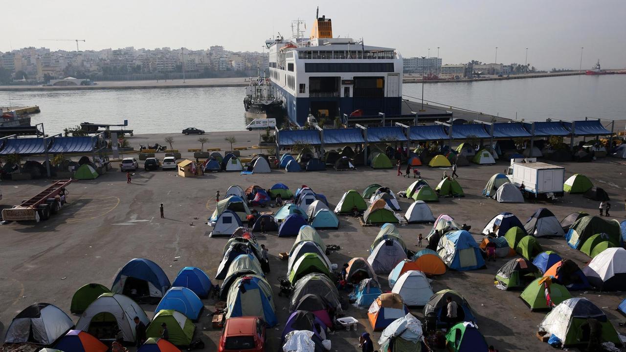 Sie sehen zahlreiche kleine Zelte am Hafen von Piräus.