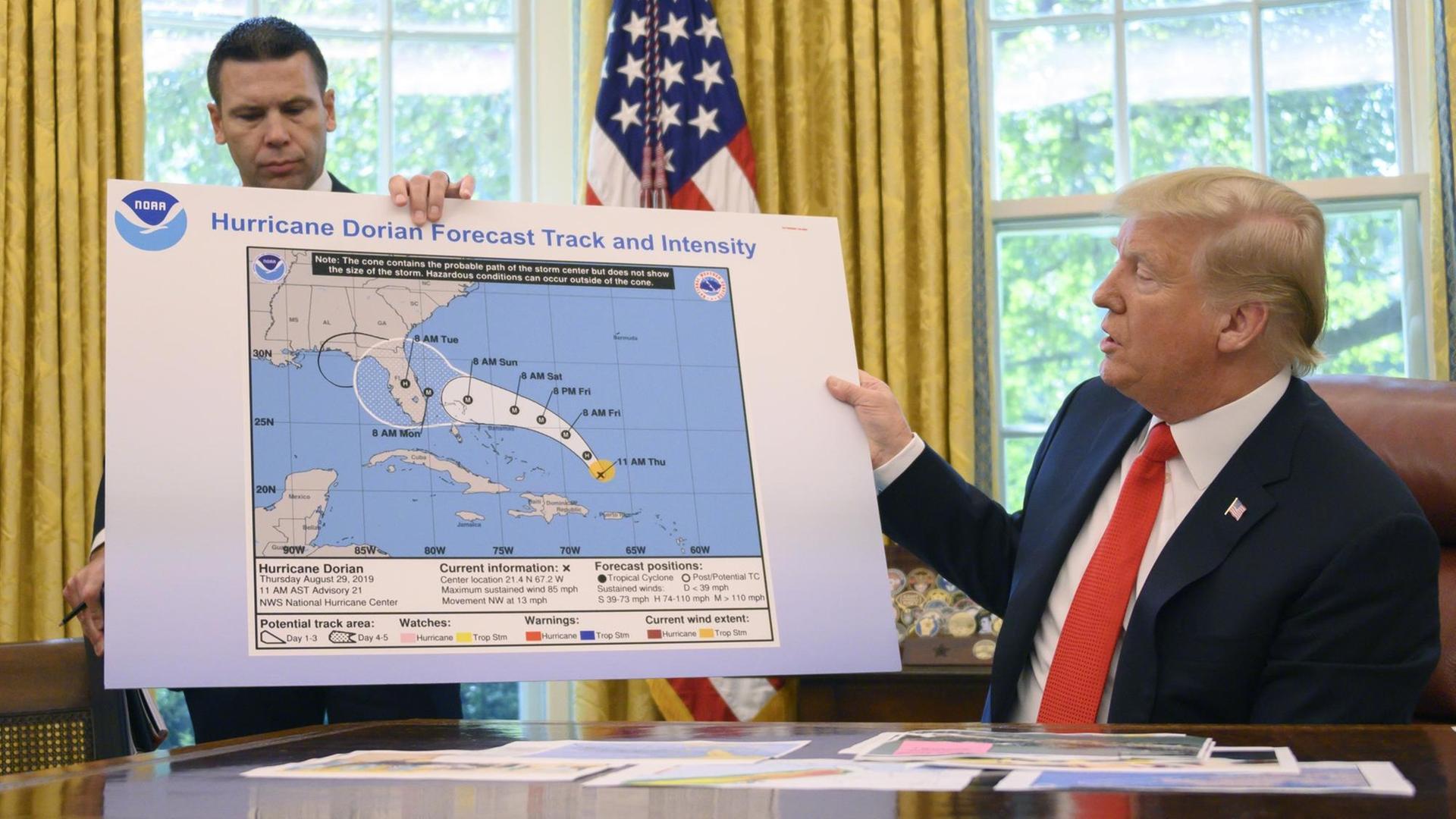 Trump hält die groß ausgedruckte Karte in die Kamera. Darauf ist in weiß die mögliche Ausbreitung des Hurrikans markiert. Das Gebiet wurde durch eine schwarze Linie vergrößert.