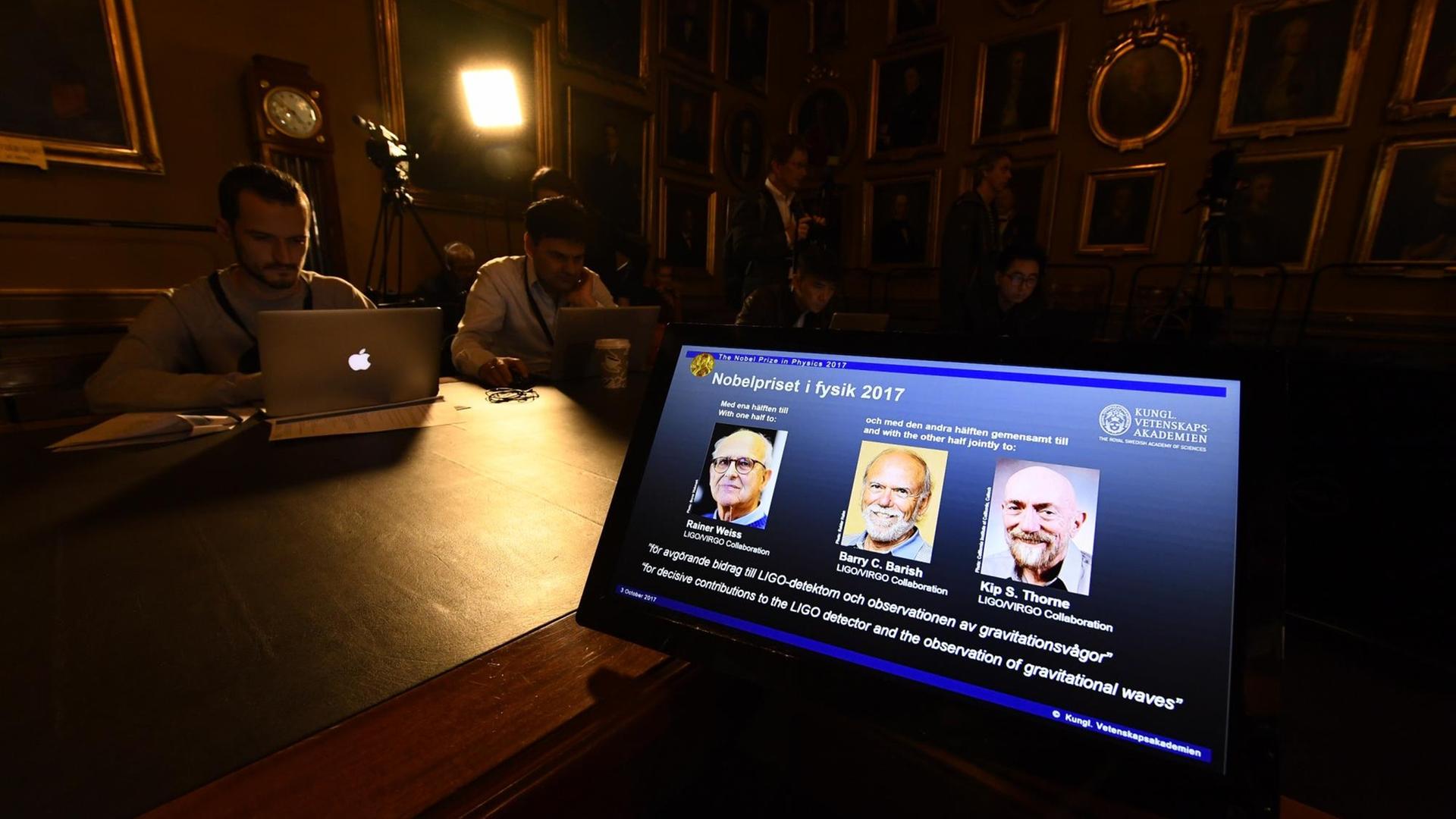 von links nach rechts: Rainer Weiss, Barry C Barish und Kip S Thorne sieht man auf dem Bildschirm eines Computers bei der Verkündung des Nobelpreises für Physik 2017