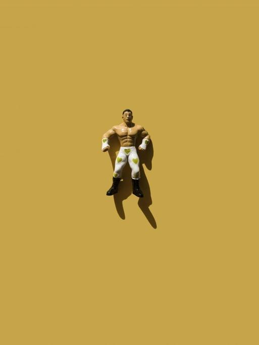 Eine Figur eines muskulösen Mannes ist auf einer Fläche abgelegt.